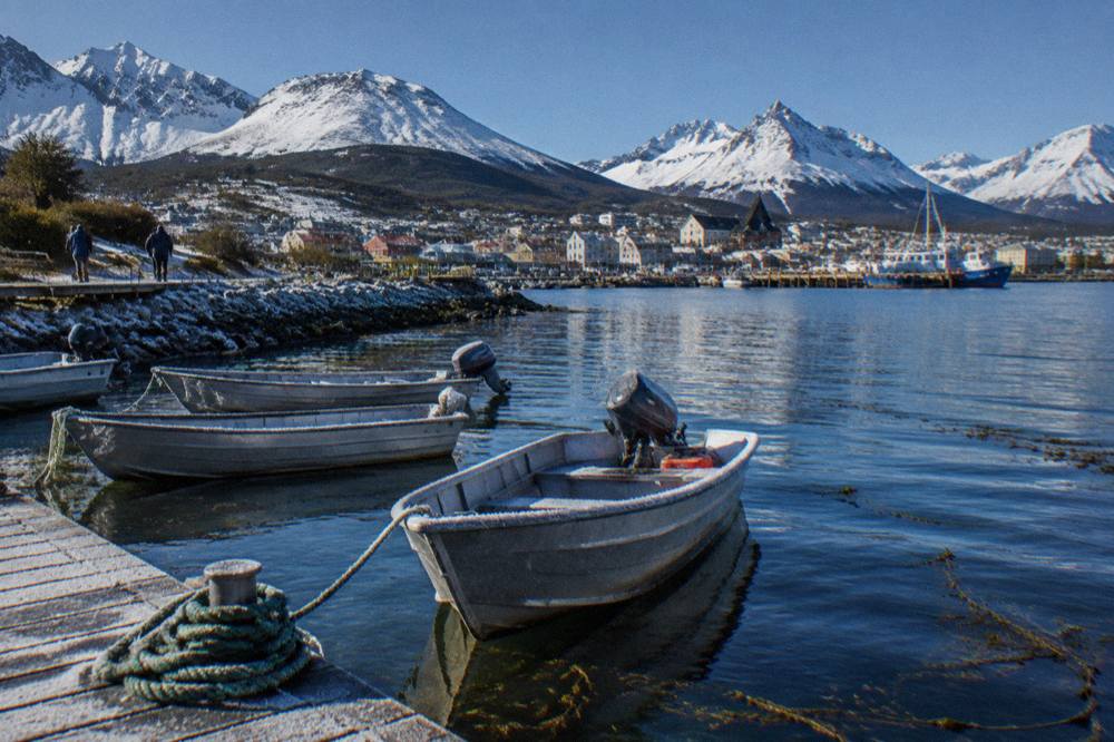 Small boats moored in Ushuaia harbour with mountains rising behind the town