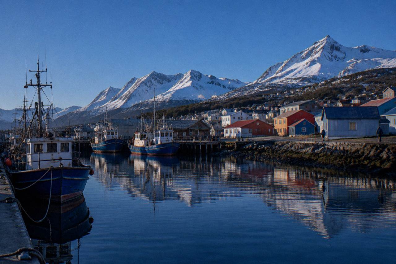 The Ushuaia waterfront with moored boats and snow-covered mountains rising behind the town