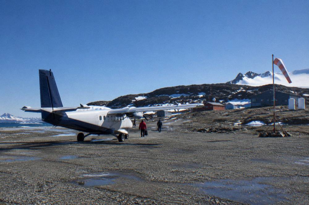 Small aircraft on a gravel runway at King George Island under an overcast Antarctic sky