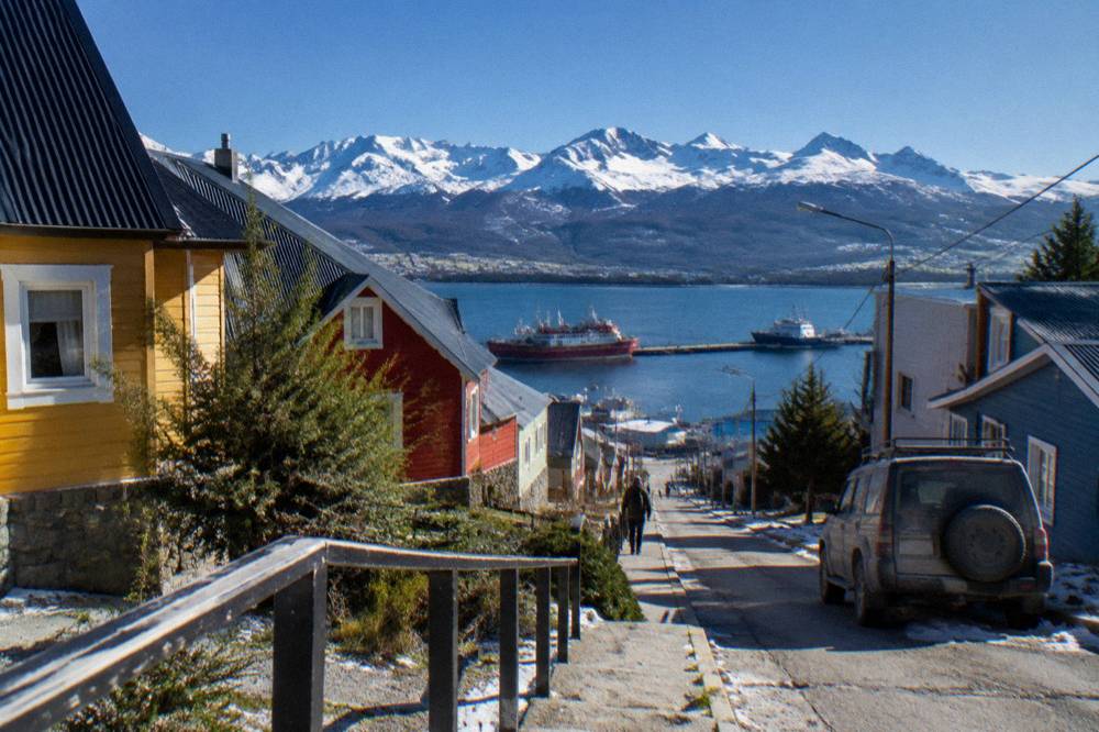 Colourful buildings of Ushuaia backed by mountains above a harbour with ships