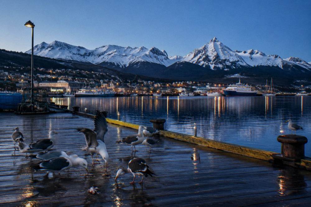 A waterfront town beneath snow-covered mountains at the southern tip of South America