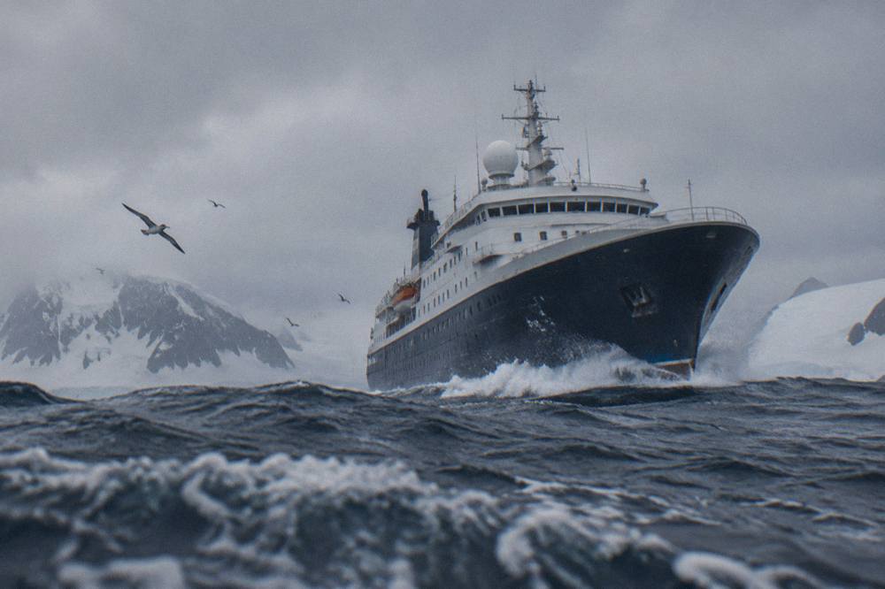 An expedition ship crossing the Drake Passage with grey skies and rolling waves