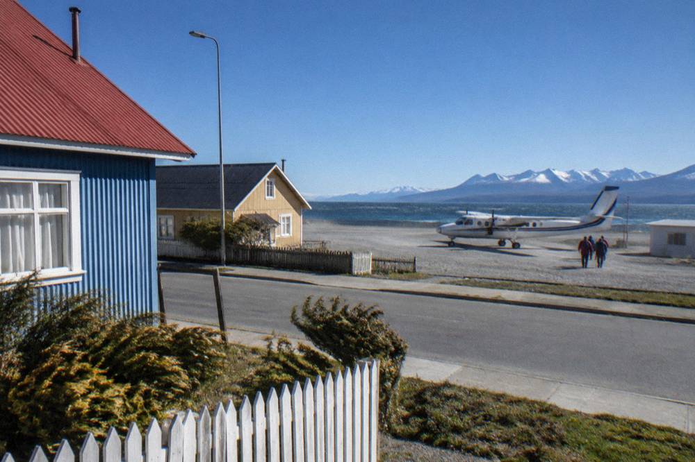 Coastal town at the southern tip of South America with mountains behind and a small plane on the runway