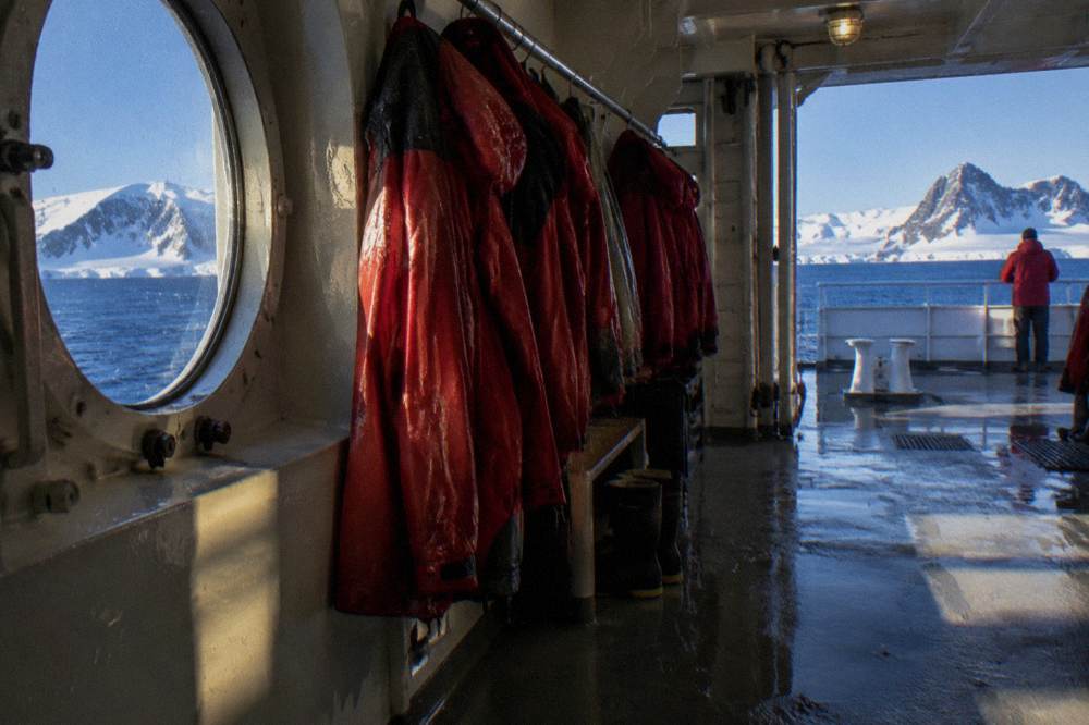 A row of red expedition parkas hanging in a wet locker aboard a small expedition ship