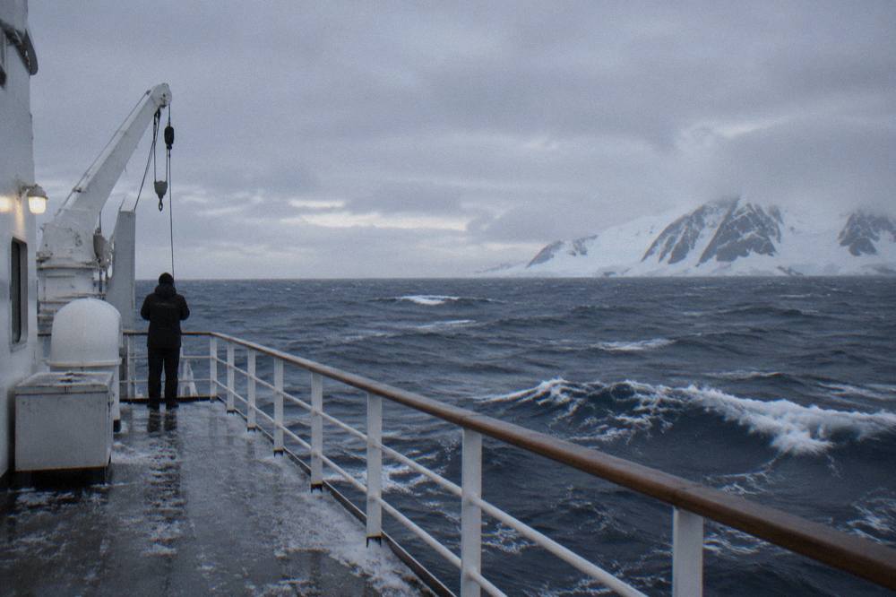 Grey open ocean swell with whitecaps seen from the deck of a ship