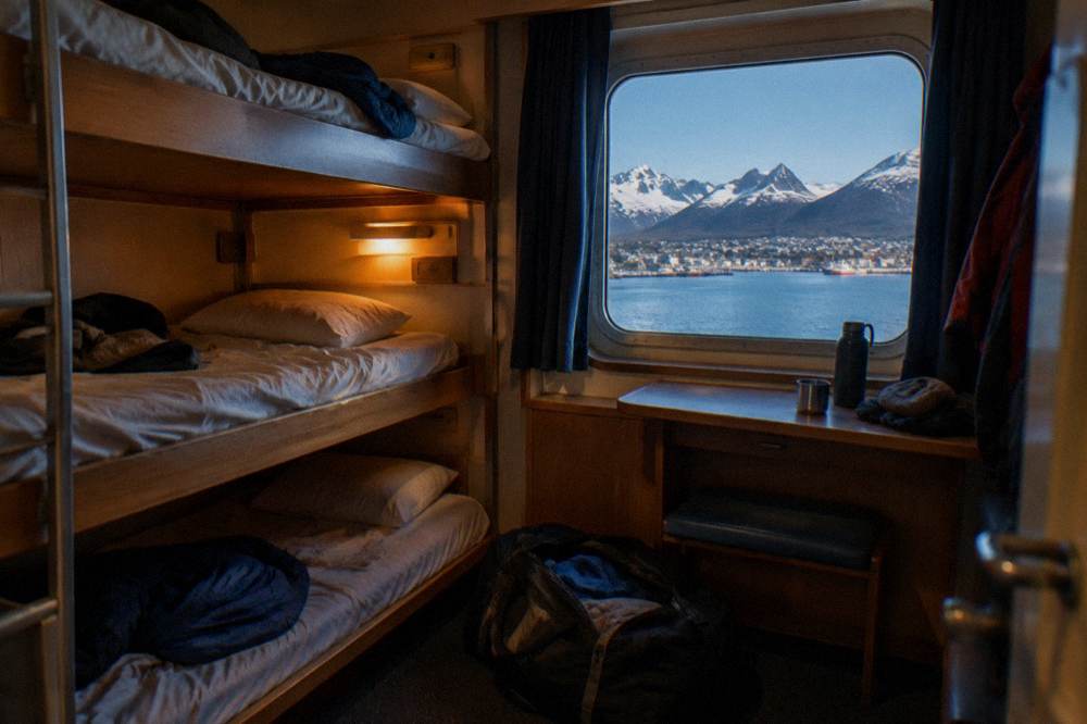 A triple-berth expedition cabin with bunks and storage showing the entry-level accommodation tier.