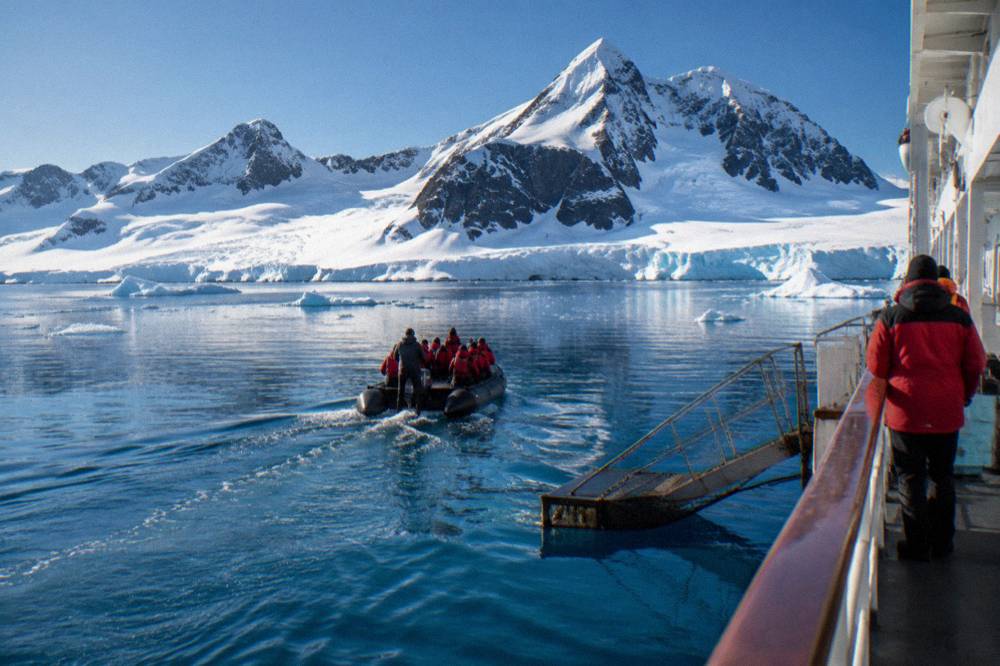 Expedition ship anchored near snow covered mountains along the Antarctic Peninsula