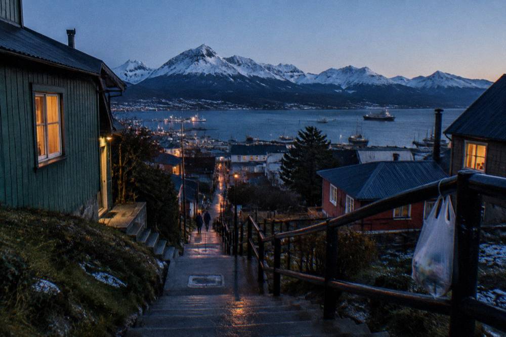 Town of Ushuaia at dusk with lights on and mountains behind