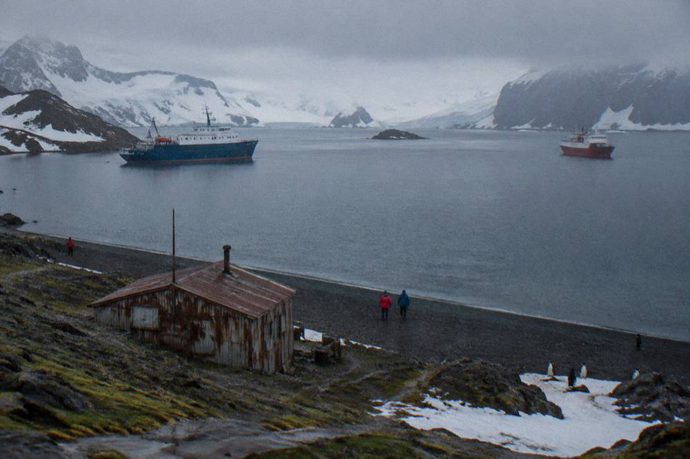Two expedition ships anchored at different ends of a sheltered Antarctic harbour