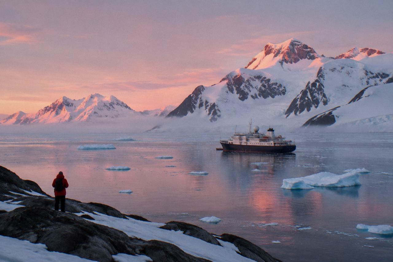 An expedition ship at anchor in an Antarctic bay surrounded by floating ice