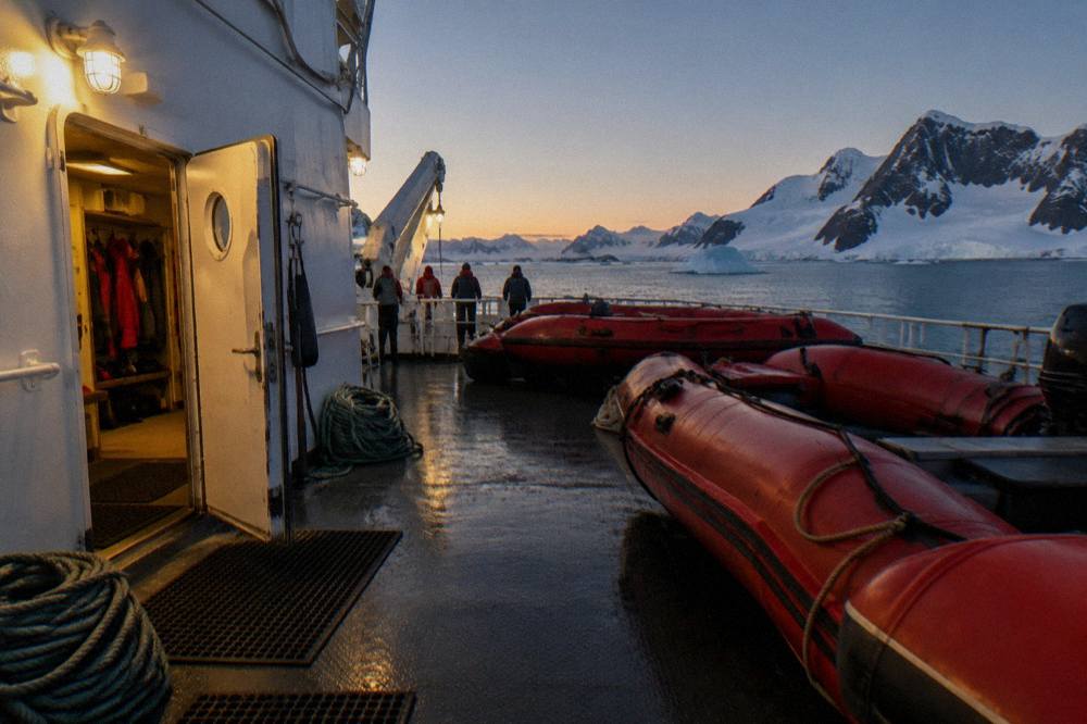 Red inflatable Zodiacs staged on the metal deck of an expedition ship beside an open mudroom door