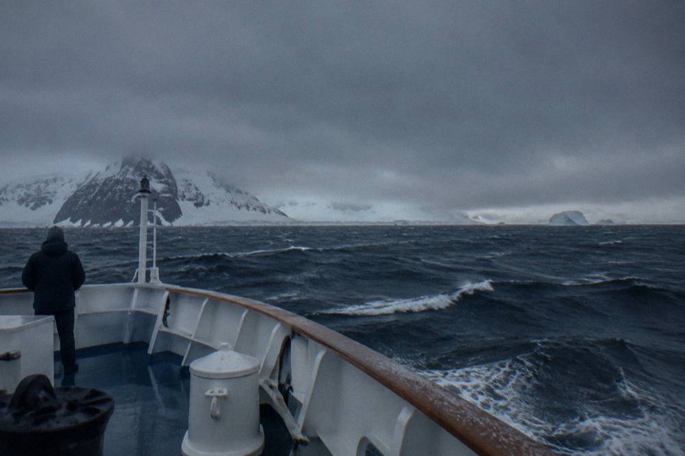 Open grey Southern Ocean with whitecaps seen from the bow of a moving ship under a low sky