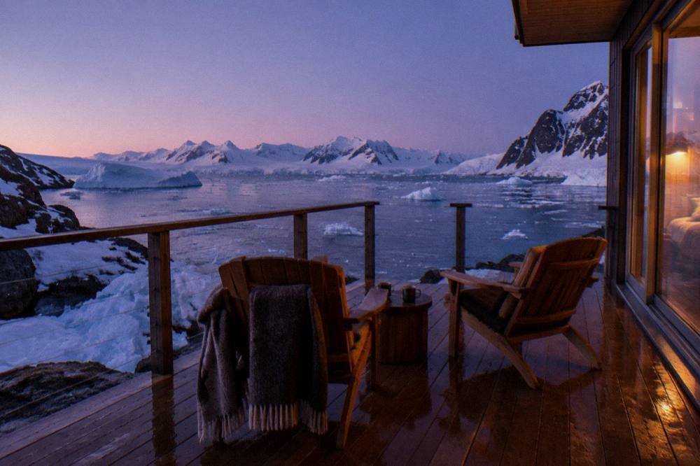 Couple's suite veranda with two chairs facing an iceberg-filled channel at dusk