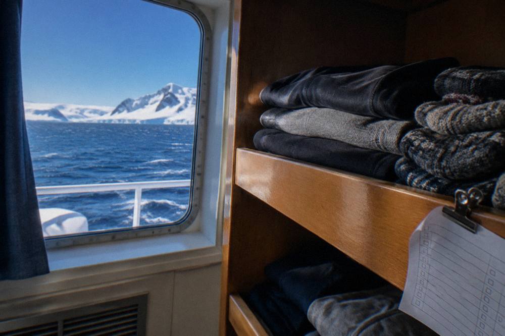 Folded thermal base layers and wool socks arranged on a wooden shelf