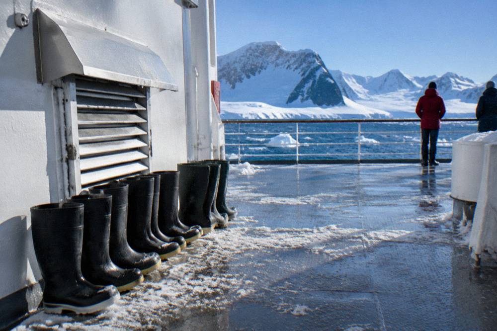 Tall rubber muck boots standing in a row on a ship deck