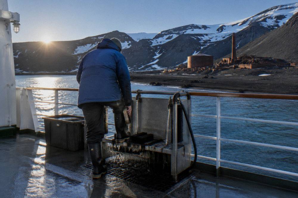 A passenger scrubbing muck boots at a ship biosecurity station