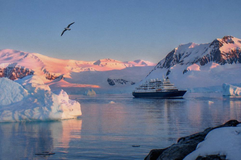 Expedition cruise ship sailing through calm polar waters near icebergs