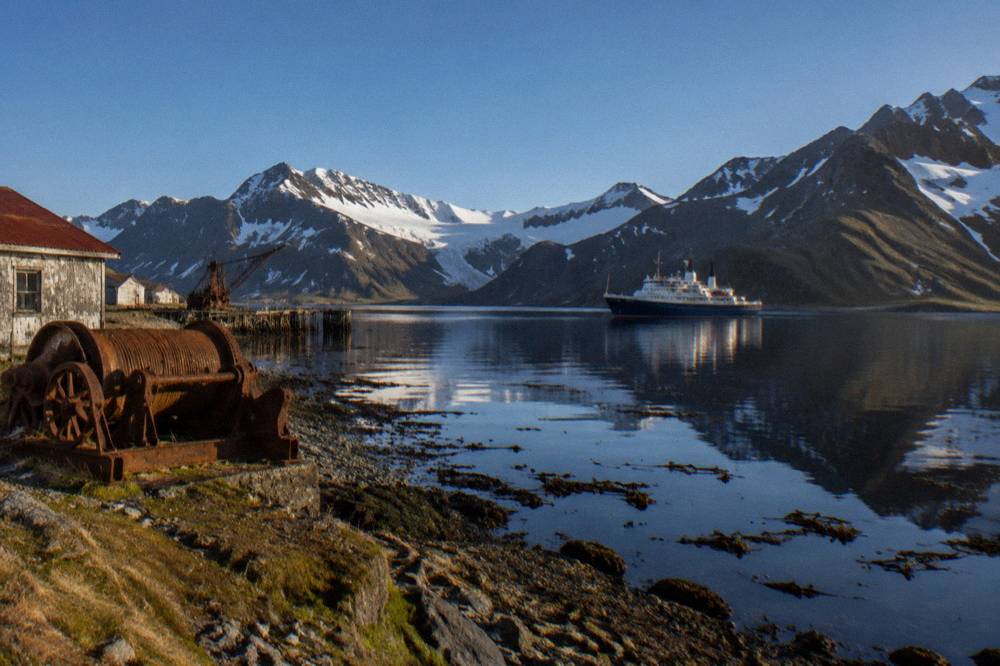 Small expedition ship anchored in a sheltered Antarctic bay surrounded by mountains