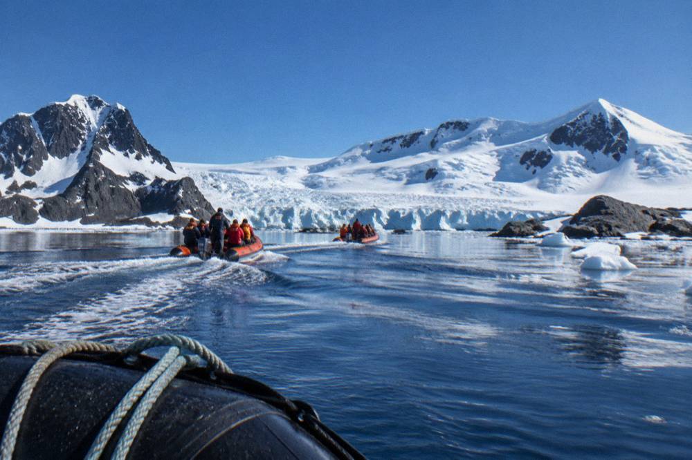 Zodiacs approaching a glacier-lined shoreline in the Antarctic Peninsula