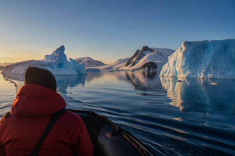 Zodiac cruising among icebergs under long January evening light