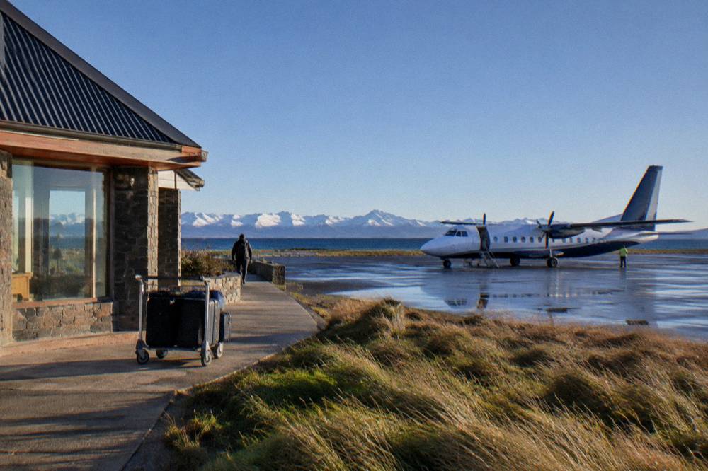A hotel and small aircraft on a windy airfield in southern Patagonia under low clouds