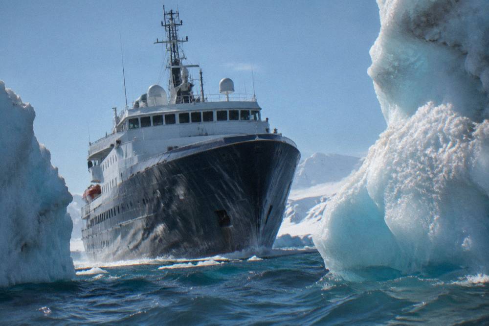 Expedition ship sailing between icebergs near the Antarctic Peninsula