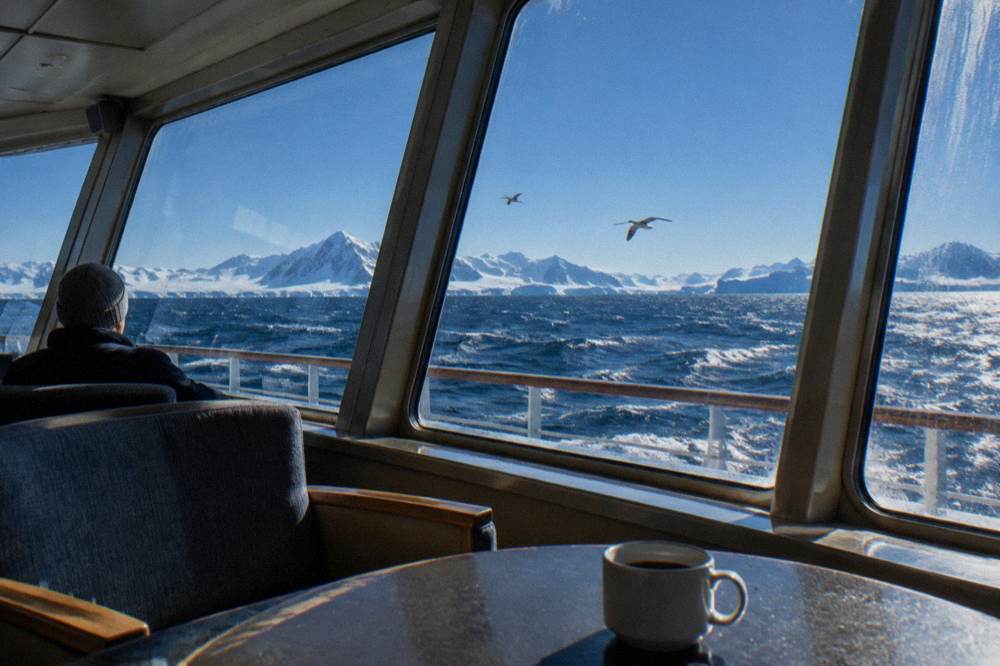 A bright ship observation lounge with panoramic windows looking out over sea ice