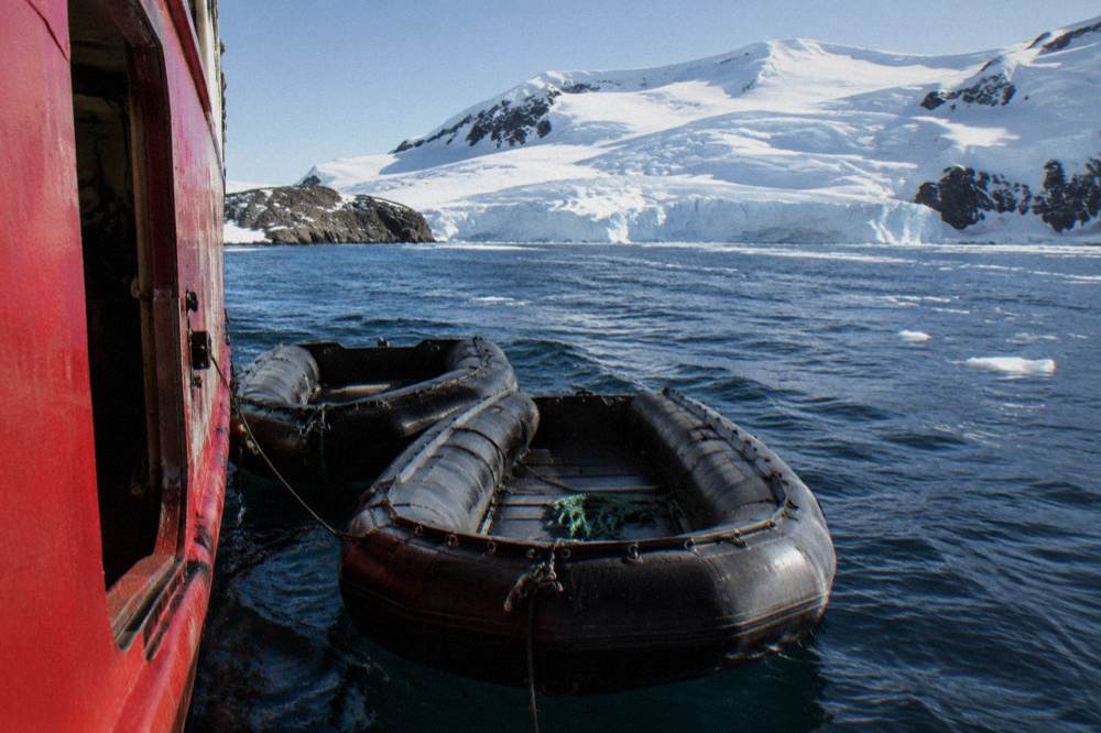 Zodiac boats tied alongside an expedition ship in a calm Antarctic bay