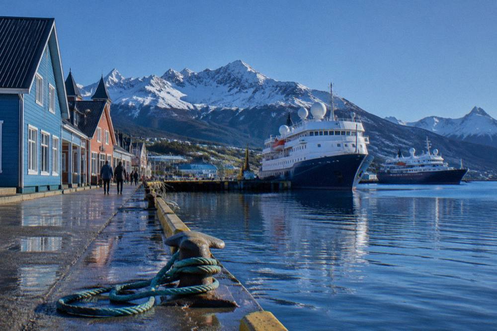 The harbour and coloured buildings of Ushuaia with expedition ships moored at the dock.
