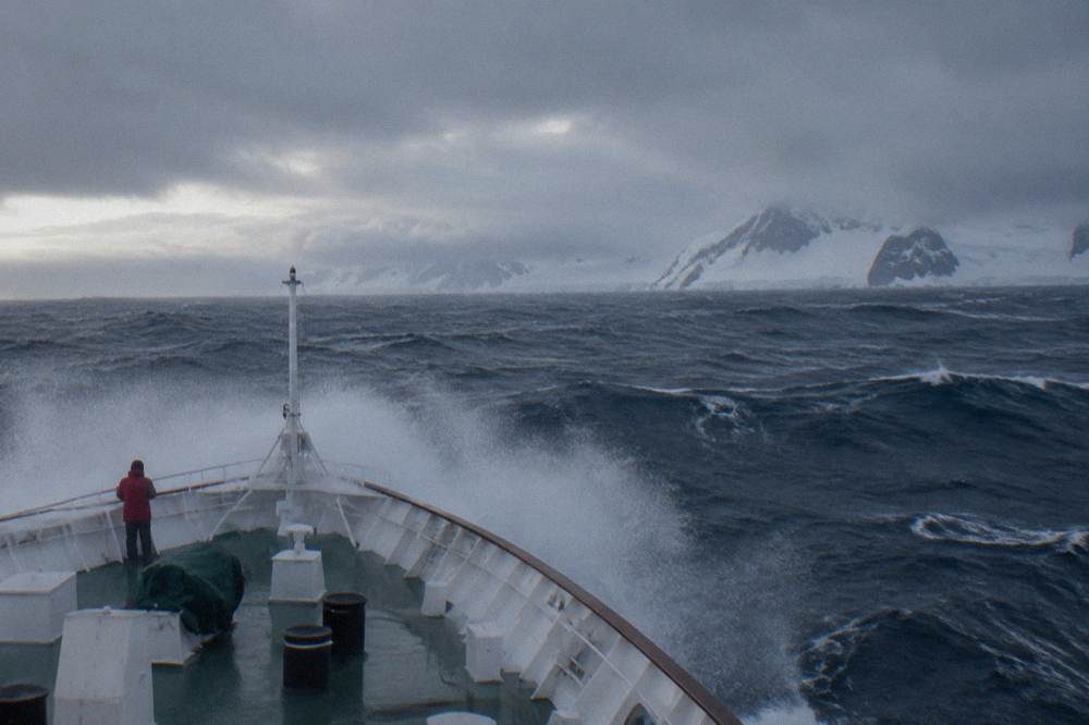 An expedition ship cutting through open ocean swells on a Drake Passage crossing.