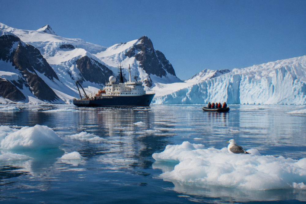 An expedition ship anchored near an ice-covered Antarctic bay