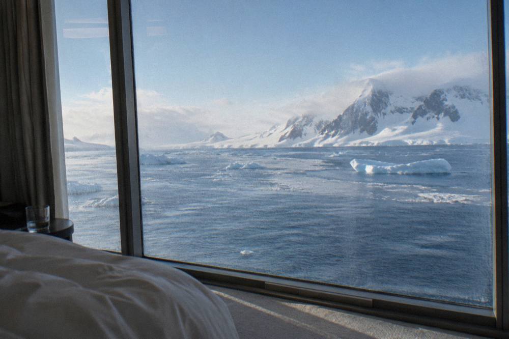 Suite interior with floor-to-ceiling windows overlooking Antarctic icebergs