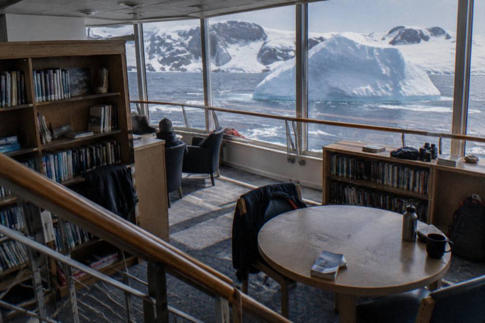 Expedition ship library lounge with panoramic windows over polar water