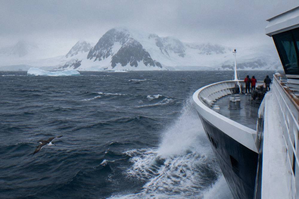 The rounded X-Bow hull of a modern expedition ship pushing through a light swell at sea