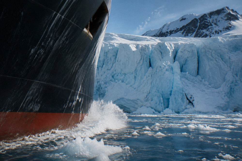 Expedition ship bow cutting through calm polar water at sunrise