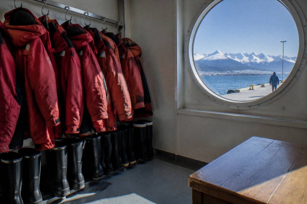 Expedition parkas and muck boots hanging in a row inside a ship readiness room