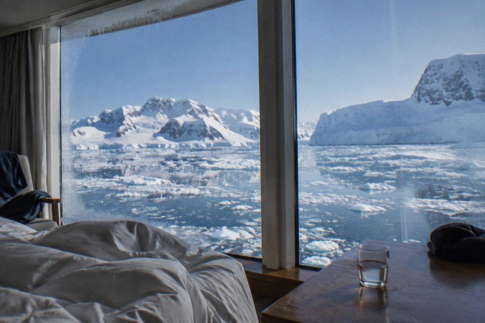 A suite interior with floor-to-ceiling windows looking out on Antarctic icebergs