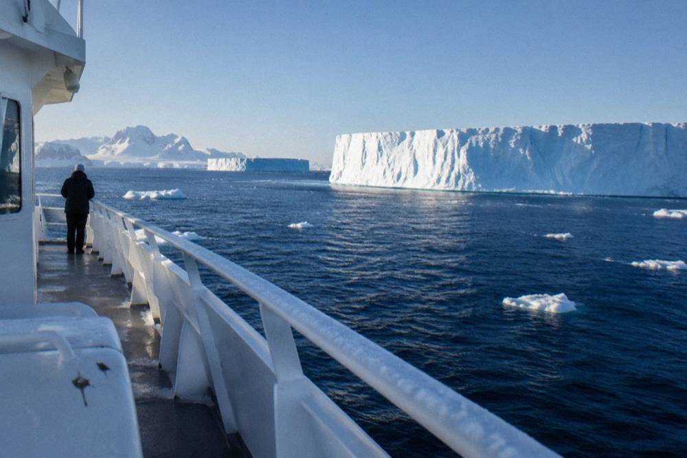 An expedition yacht cruising past flat-topped icebergs near the Antarctic Peninsula
