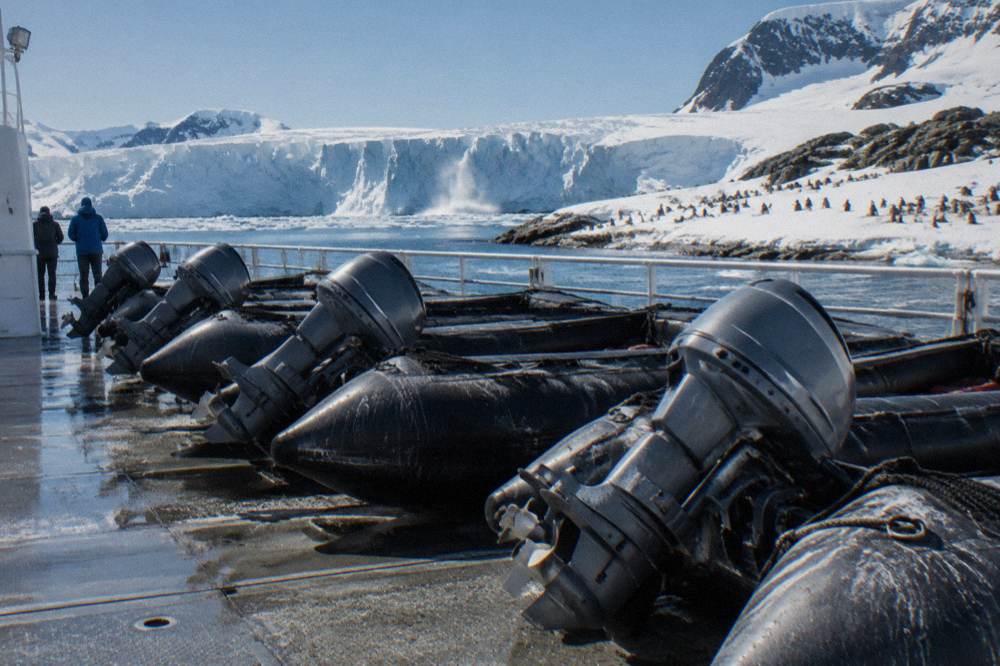 Zodiacs lined up on a ship deck beside a snowy Antarctic landing site