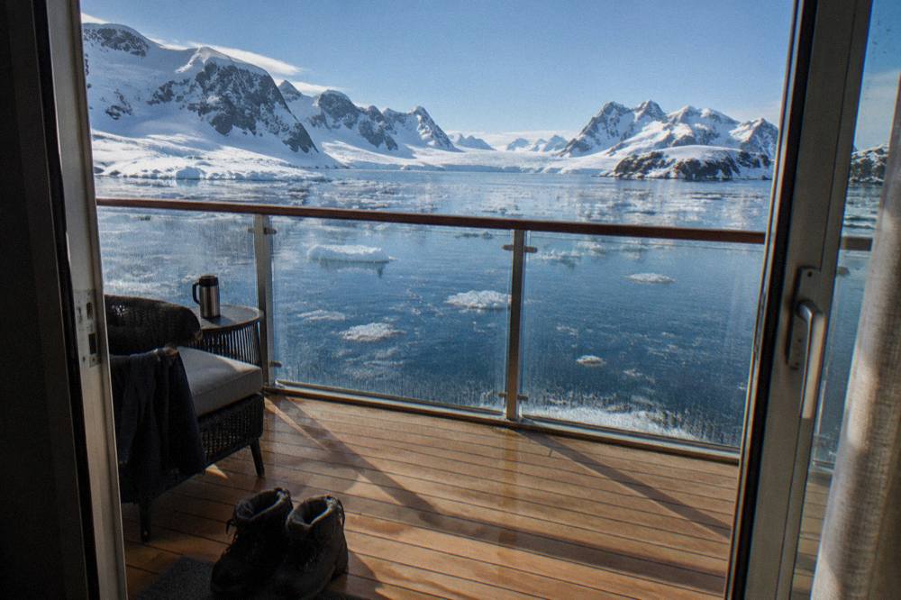 A suite balcony overlooking calm polar water with low ice floes