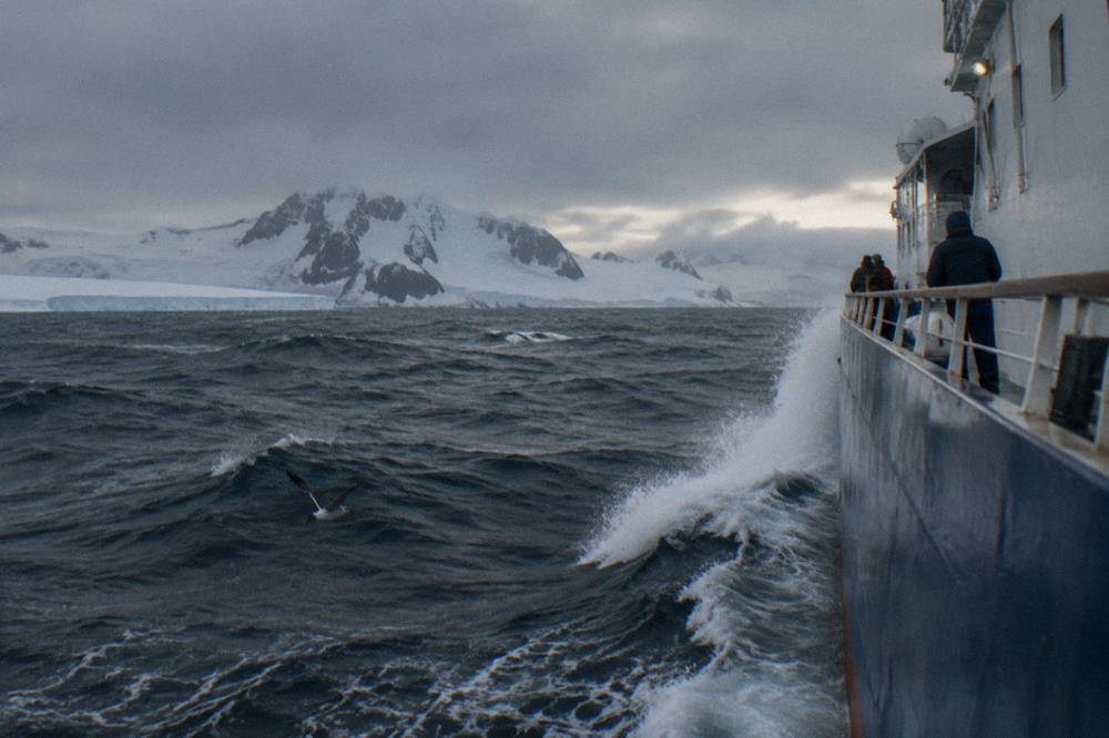 Expedition ship ploughing through open grey ocean swell on a Drake Passage crossing