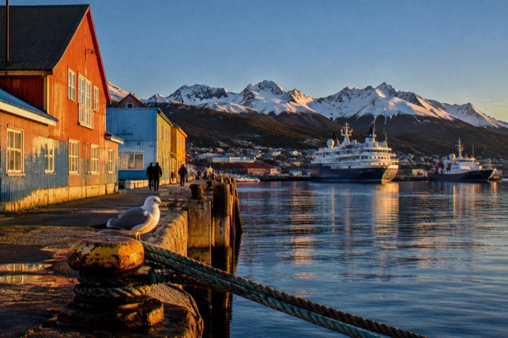 Colourful waterfront buildings in Ushuaia with expedition ships docked in the harbour