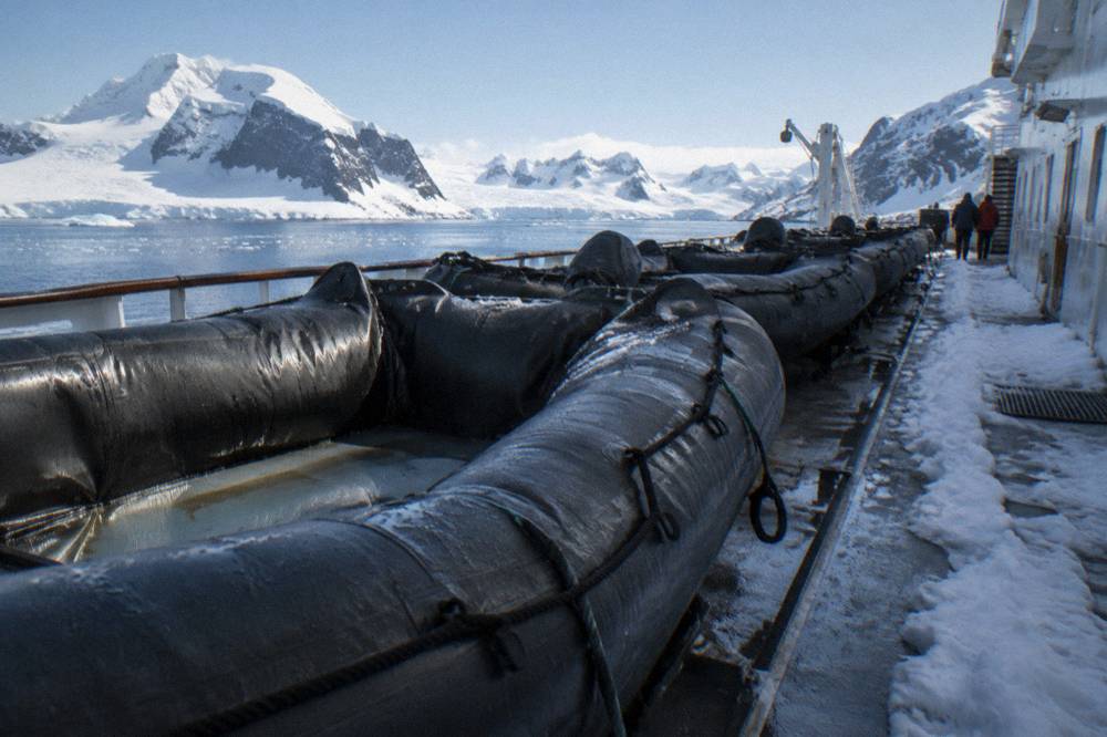Zodiacs lined up on an expedition ship's deck beside a snowy gangway