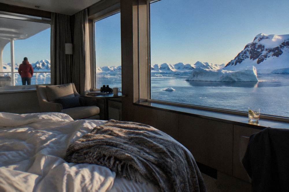 Elegant ship suite interior with large windows looking out over icebergs