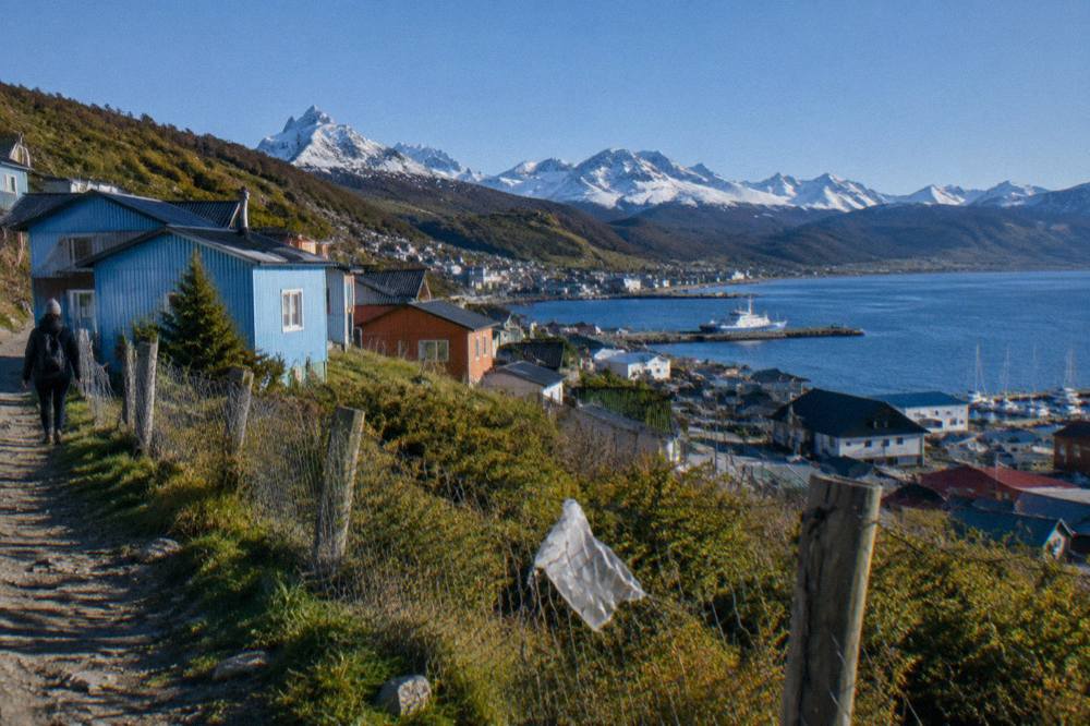 Colorful buildings of Ushuaia rising up the hillside with the Beagle Channel and mountains beyond