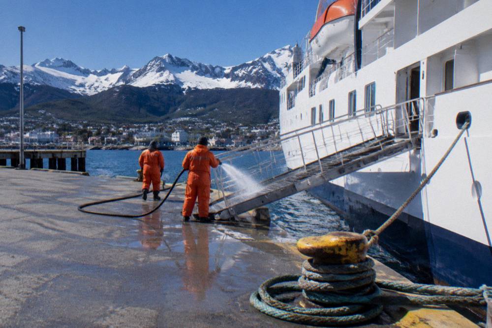 Expedition cruise ship tied up at the Ushuaia pier with crew preparing the gangway