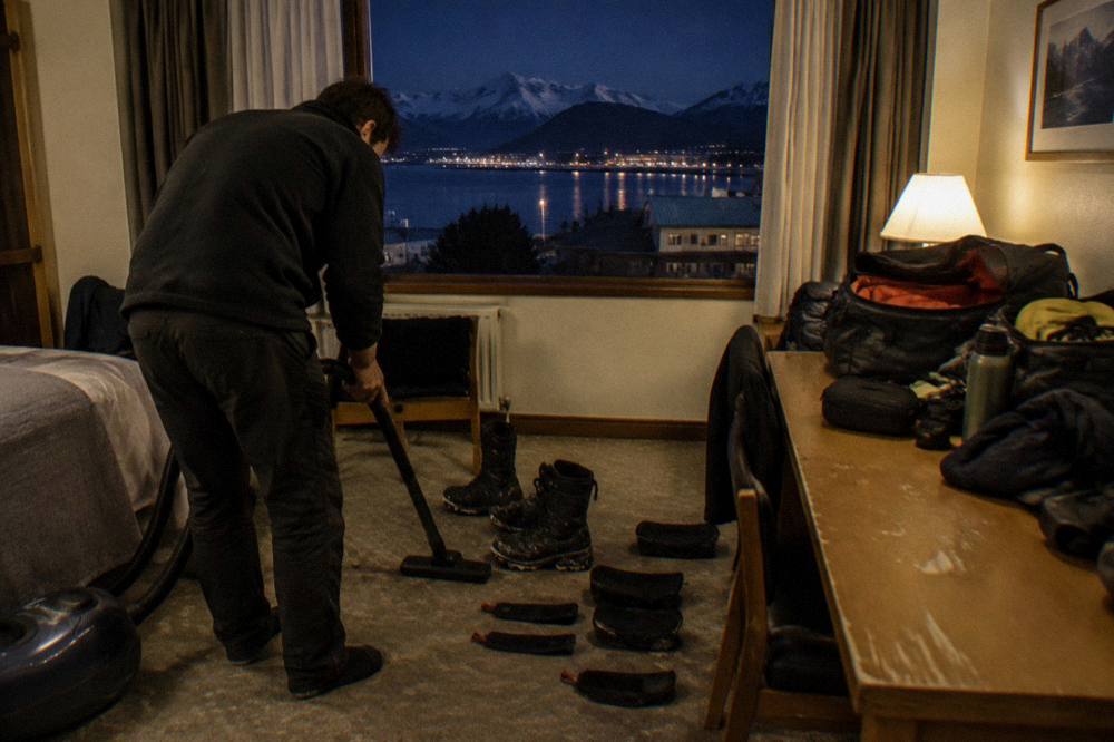 Expedition passengers cleaning and velcroing gear in a hotel room before boarding in Ushuaia