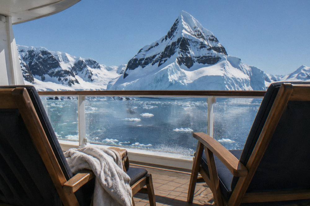 A cruise ship cabin veranda with two chairs facing Antarctic icebergs
