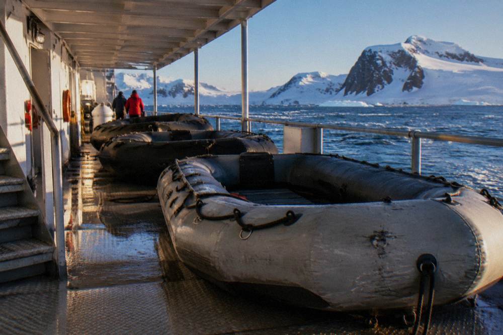 Zodiac boats lined up on a ship deck beside a sheltered boarding platform